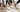 Marketing team reviewing plain sample drink bottles, notebooks, tote bags and colour swatches on an office table before ordering branded merchandise